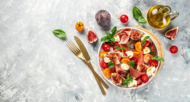 Hafif arka planda domates, incir ve mozzarella salatası. Uzun afiş biçimi. en üstteki görünüm.