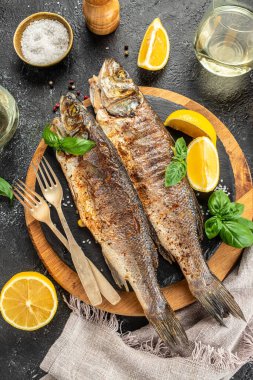 Koyu bir arka planda leziz ızgara balık deniz kabuğu. dikey görüntü. Üst Manzara. metin için yer.