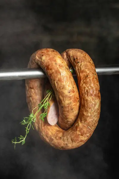 chicken sausage smoking processes on a dark background. place for text,