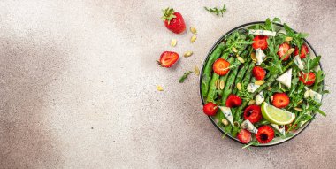 Sağlıklı yeşil salata yaprakları, taze çilek dilimleri. Sağlıklı ve dengeli beslenme kavramı. Uzun afiş biçimi. en üstteki görünüm.