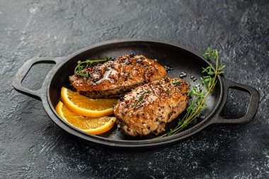 Tavada kekik ve portakallı kızarmış ördek eti. Karanlık bir arka planda. Üst Manzara. Boşluğu kopyala.