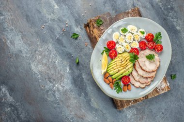 Keto Gıda avokadosu, haşlanmış bıldırcın yumurtası, tavuk fileto ve vişneli domates tabağı. Restoran menüsü, diyet, yemek kitabı tarifi üst görünümü.