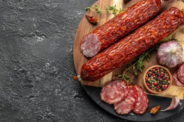 Kesme tahtasındaki kuru salam dilimleri koyu bir arka planda. Üst Manzara. metin için boşluk kopyala.