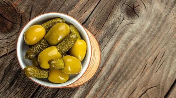 Green olives stuffed with cucumbers on a wooden background. Long banner format. top view. copy space for text.