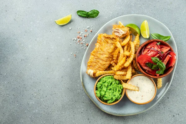 Crispy Fish and Chips served with mashed peas, vegetable salad, tartar sauce, Traditional British food, place for text, top view,