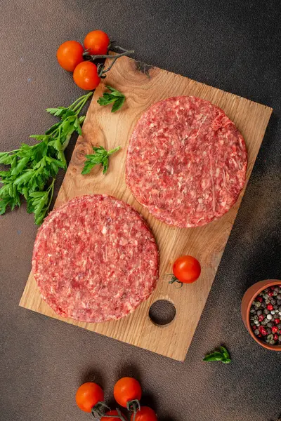 Raw Ground beef meat Burger steak cutlets on a wooden board, Food recipe background. Close up,