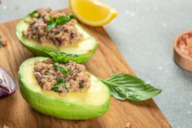 Tahtaya konmuş ton balıklı avokado. Sağlıklı ve dengeli beslenme kavramını arka planda açık arka planda tut. Boşluğu kopyala,