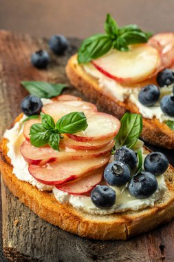 Krem peynirli, ballı, şeftalili ve yaban mersinli lezzetli tost. Sağlıklı ve dengeli beslenme kavramı. dikey görüntü. Üst Manzara. metin için boşluk kopyala.