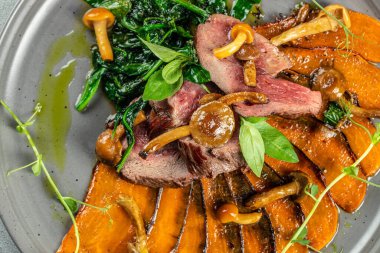 Fırında patates ve taze yeşilliklerle servis edilmiş baharatlı dana biftek..