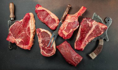 Çiğ Black Angus Prime bifteği T-bone, tomahawk, New York bifteği çeşitleri. Çiğ mermer sığır filetosu bifteği koyun. metin için yer, üst görünüm.