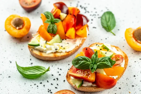 Gourmet sandwiches bread toast, bruschetta with cream cheese, peaches, tomatoes and green basil leaves,