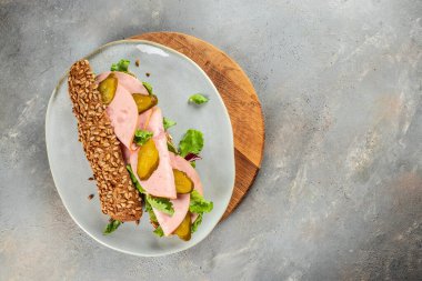 Ahşap bir tahtanın üzerinde salatalık turşusu ve jambonlu lezzetli baget sandviç. Üst Manzara. metin için boşluk kopyala.
