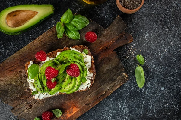 Avocado Toast for breakfast or lunch with avocado, raspberries, cream cheese and chia seeds. Vegetarian food. Clean eating. Top view. Copy space,