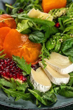 Hurmalı sağlıklı salata, taze yeşillik, avokado, peynirli ve nar. dikey görüntü. Üst Manzara. metin için boşluk kopyala.