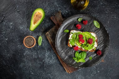 Kahvaltıda avokado tostu ya da avokado, ahududu, krem peynir ve chia tohumlarıyla öğle yemeği. Vejetaryen yemeği. Temiz yemek. Üst Manzara. Boşluğu kopyala,