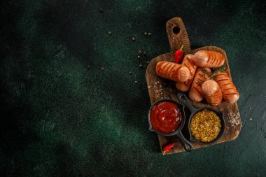 Ahşap bir tahtanın üstünde soslu ızgara sosisler, üst manzara. Boşluğu kopyala.