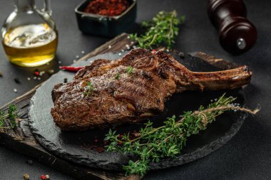 Tomahawk bifteği, arka planda baharatlar ve otlarla birlikte. Üst Manzara. metin için boşluk kopyala.