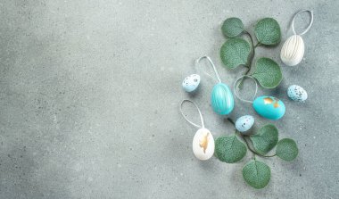 Yumurtaların Paskalya çerçevesi ve gri arka planda yeşil yapraklar. Mutlu Paskalya tatili konsepti.