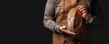 Fırıncının elinde bir somun taze ekmek. Uzun afiş biçimi. metin için boşluk kopyala.