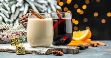Sıcak şarap ve eggnog bardaklarıyla sıcak bir atmosfer Noel kış alkolü Noel ışıklarıyla süslenmiş..