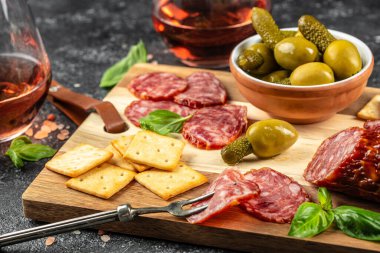 Taş zeminde salam, peynir, ekmek ve zeytinli Antipasto tahtası.