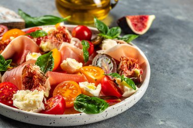 İncirli taze salata, mozzarella, incir, prosciutto taze fesleğen yaprağı ve domates sağlıklı ve dengeli yemek kavramı. metin için yer, üst görünüm,