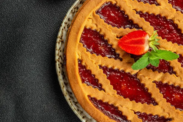 delicious baked Italian jam cake crostata strawberry pie on a dark background. Restaurant menu, dieting, cookbook recipe top view.