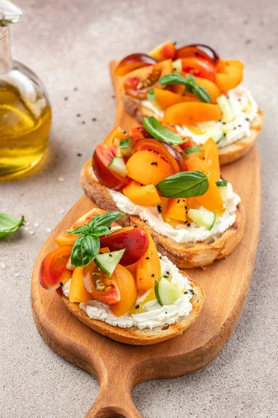 Gourmet sandwiches bread toast, bruschetta with cream cheese, peaches, tomatoes and green basil leaves,