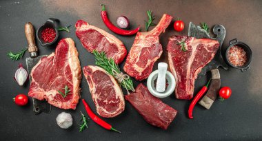 Ahşap bir tahtanın üzerinde büyük çiğ biftek. Biftek ve arka planda et satırı. en üstteki görünüm.