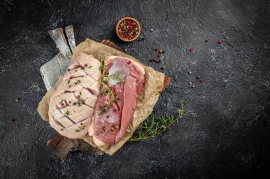 Çiğ ördek göğsü. Esmer arka planda otlar ve baharatlar var. metin için boşluk kopyala. en üstteki görünüm.
