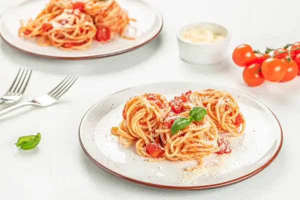 italian spaghetti pasta with tomato sauce, cheese parmesan and basil on white background, top view.