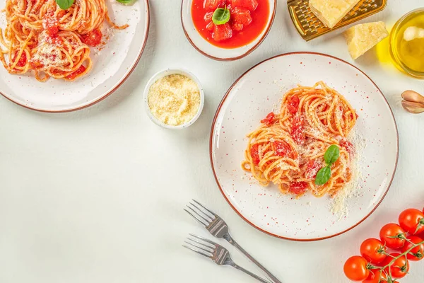 pasta with tomato in red sauce on a white plate over light grey slate, stone or concrete background,