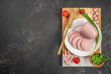 Karanlık bir arka planda dilimlenmiş jambonlu sosis. Üst Manzara. metin için boşluk kopyala.