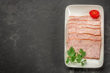 Koyu arkaplanda tabakta kare jambon dilimleri. Üst Manzara. metin için boşluk kopyala,