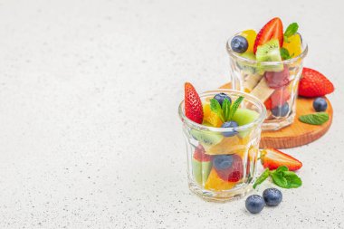 meyve tatlısı, arka planda taze yaz meyveleri, kivi, muz, çilek, limon, yabanmersini ve portakal. sağlıklı yaz konsepti.