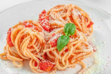 Domates soslu spagetti makarna ve beyaz tabakta taze yeşil fesleğen. Yemek tarifi geçmişi. Kapat..