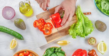 Erkek şef mutfaktaki tahta tahtada sebzeleri bıçakla kesip biçiyor. Vegan ya da diyet gıda konsepti.