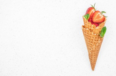 Taze çilek ve dondurma külahları, arka planda waffle külahında böğürtlen meyvesi, üst manzara. Boşluğu kopyala,