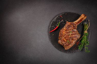 Tomahawk bifteği, arka planda baharatlar ve otlarla birlikte. Üst Manzara. metin için boşluk kopyala.