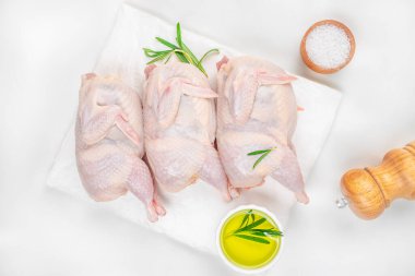 Beyaz masadaki bitkilerle nefis çiğ bıldırcın eti.,