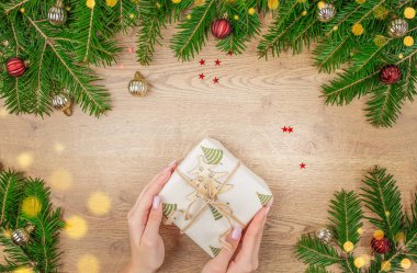 Bir bayanın elleri Noel hediyesi kutusunu ahşap masada süsledi. Noel kartı. Üst Manzara. Boşluğu kopyala