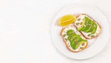 Healthy food, Two avocado toasts with cream cheese and seeds for breakfast on white table background, top view. clipart