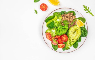 Avokado, brokoli, kinoa, domates ve beyaz arka plan manzaralı taze otlarla dolu sağlıklı bir vejetaryen yemek kasesi. Boşluğu kopyala,