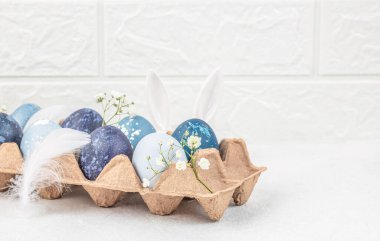 Çiçekli Paskalya yumurtaları beyaz arka planda kağıt tepside bahar çiçekleri. Paskalya kartı. Üst Manzara. Boşluğu kopyala.