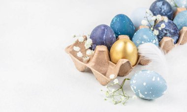 Çiçekli Paskalya yumurtaları beyaz arka planda kağıt tepside bahar çiçekleri. Paskalya kartı. Üst Manzara. Boşluğu kopyala.