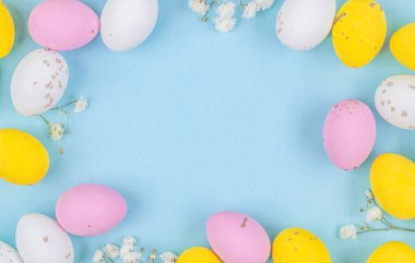 Renkli Paskalya yumurtası kenarı pastel mavi kağıt arka planda. Boşluğu kopyala.