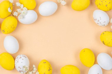 Sarı arka planda beyaz yumurta ve sarı yumurta. Minimalist Paskalya dairesi zarif dekorasyonlarla benekli yumurtalar içeriyor..