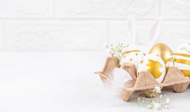 Karton bir paketin içine boyanmış Paskalya yumurtaları ve açık arkaplanda çiçekler. Mutlu Paskalyalar. Boşluğu kopyala.