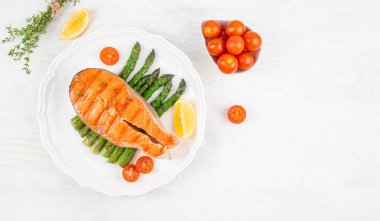 Beyaz arka planda ızgara somon balığı bifteği kuşkonmaz..