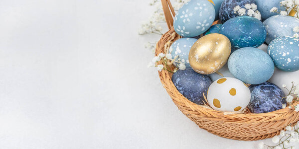 painted eggs for Easter in basket with flowers on light background. Happy easter concept. copy space.